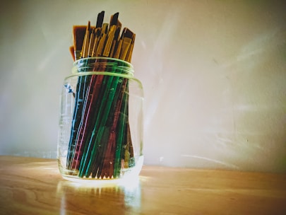 A serene studio corner with canvases stacked and brushes resting in jars.