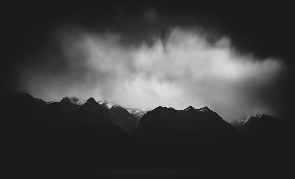 grayscale photo of mountains under cloudy sky