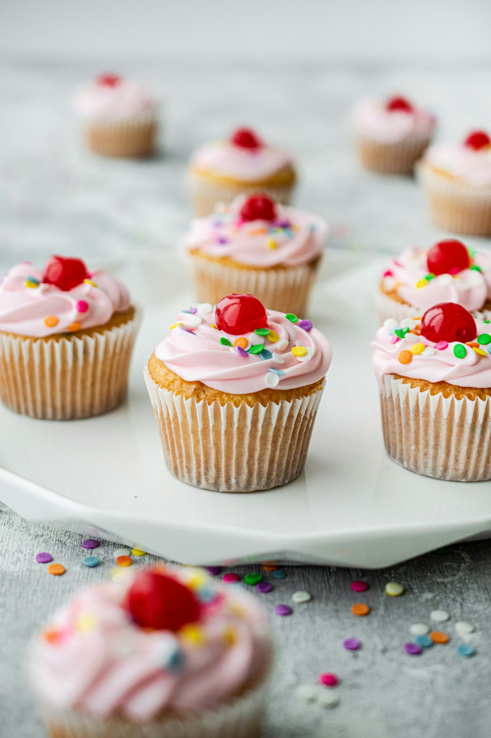 cupcakes com cereja rosa na placa de cerâmica branca