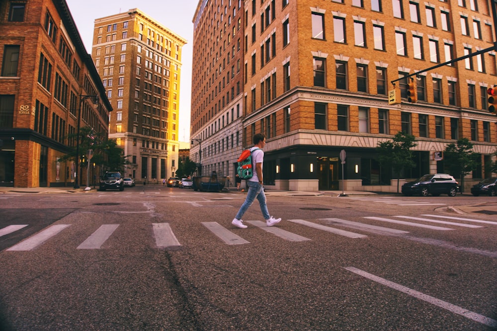 man in white shirt and gray pants walking on pedestrian lane during daytime