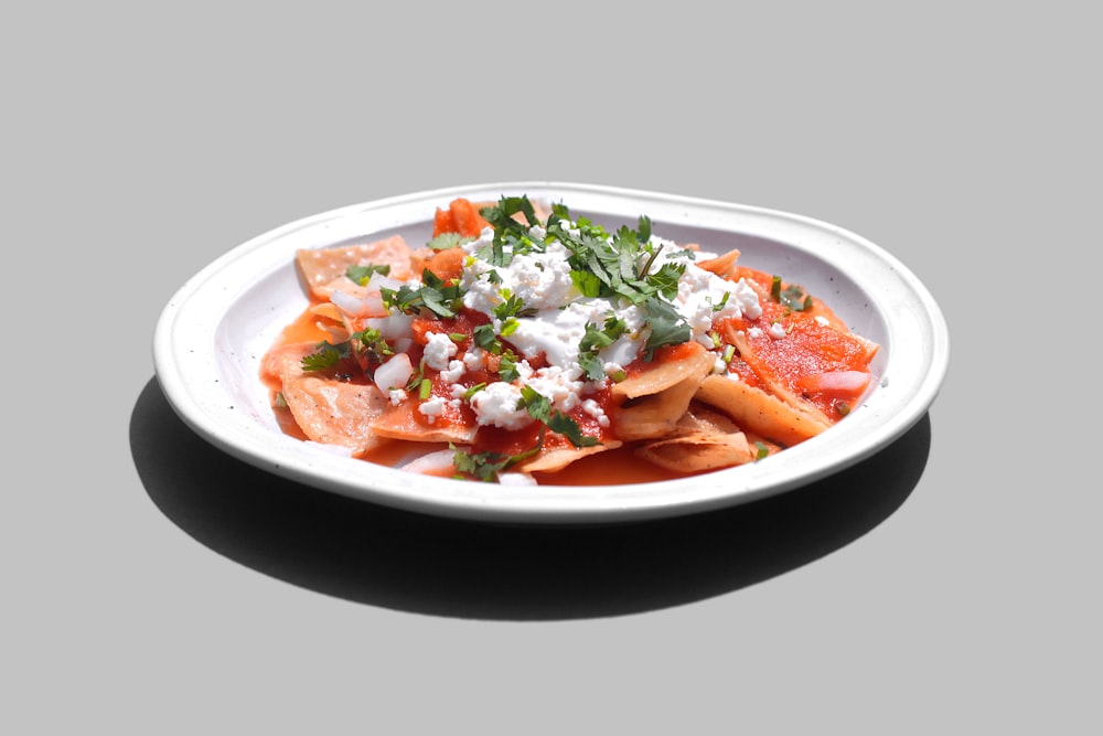 sliced carrots and green leaf vegetable in white ceramic bowl