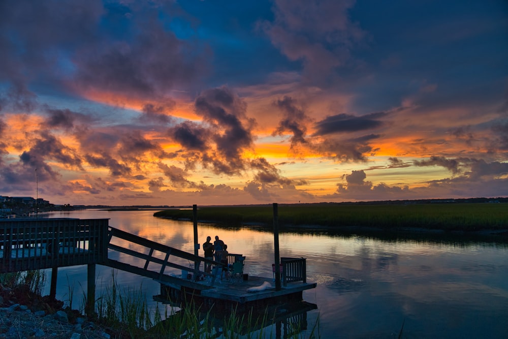 silhouette of people on dock during sunset