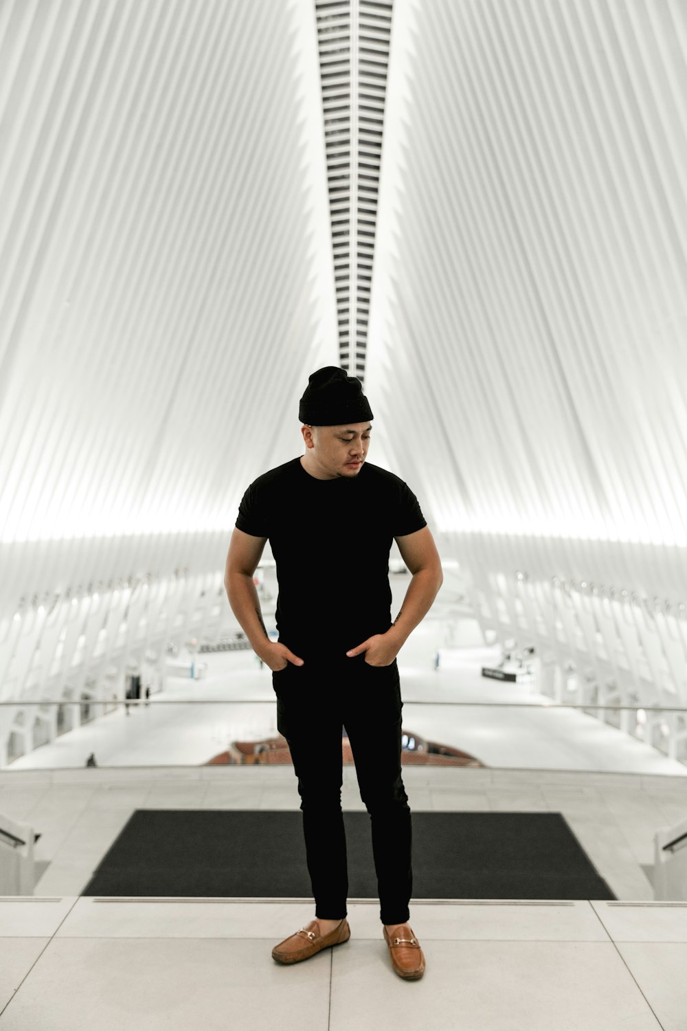 man in black crew neck t-shirt standing on white concrete building