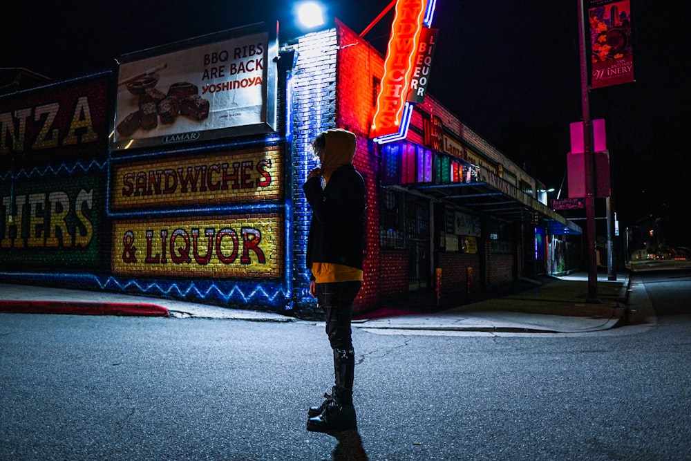 woman in red and black long sleeve shirt and black pants standing on road during night