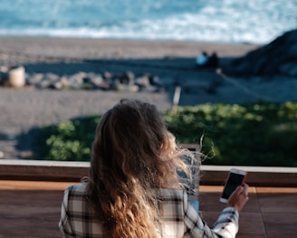 woman in white and black plaid shirt holding black smartphone