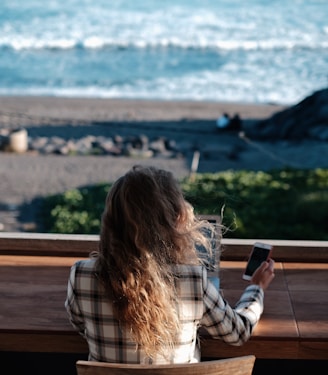 woman in white and black plaid shirt holding black smartphone