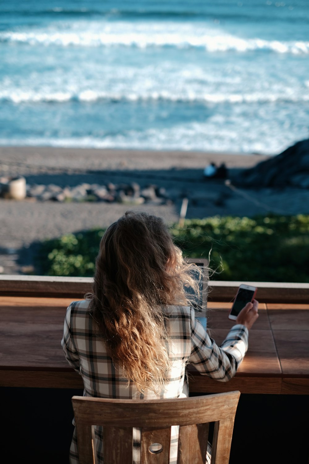 woman in white and black plaid shirt holding black smartphone