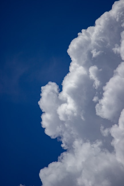 A large, fluffy cumulus cloud against a deep blue sky, showing a gradual transition from the white cloud to the clear blue background.