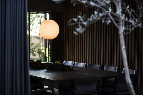 A warm dining room featuring a wooden extendable table surrounded by soft fabric chairs bathed in gentle pendant light.