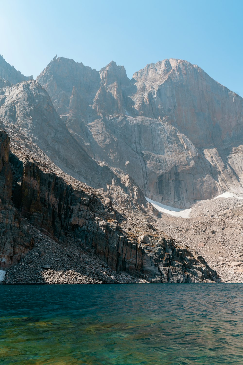 Montagne rocheuse brune au bord du plan d’eau pendant la journée