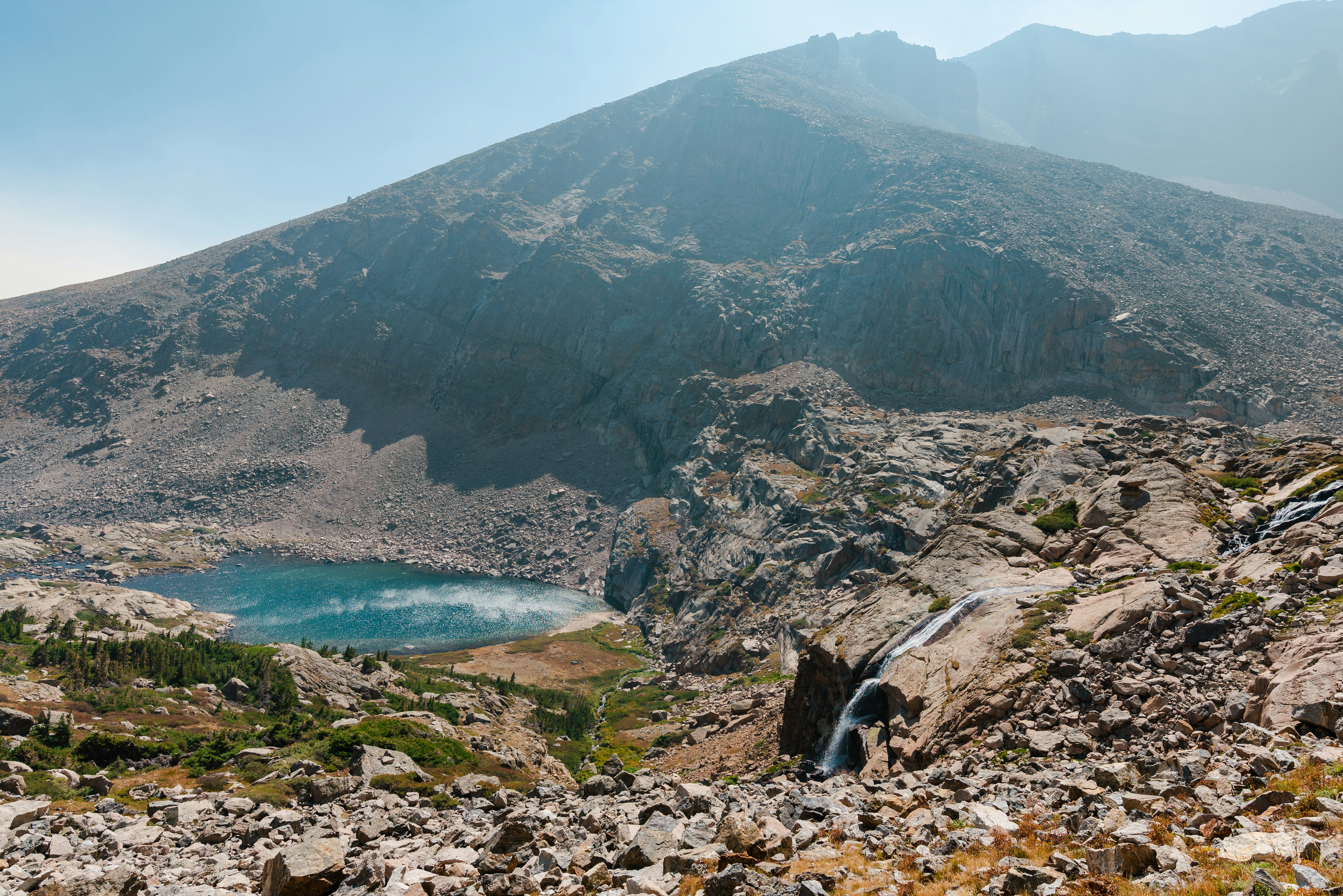 brown rocky mountain beside blue sea under blue sky during daytime