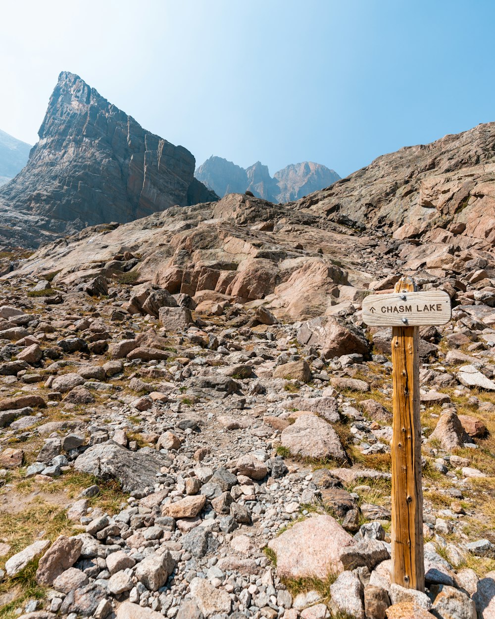 brown wooden post on rocky ground near rocky mountains during daytime