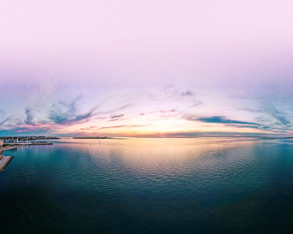 body of water under white clouds during daytime