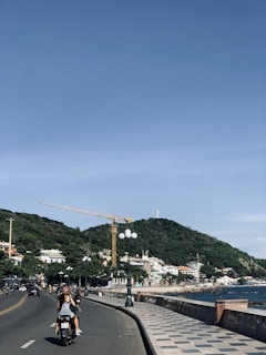 A rider cruising along a coastal road with ocean waves in the background