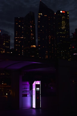 A sleek, secure kiosk enclosure with a glowing touchscreen interface, set against a modern urban backdrop.