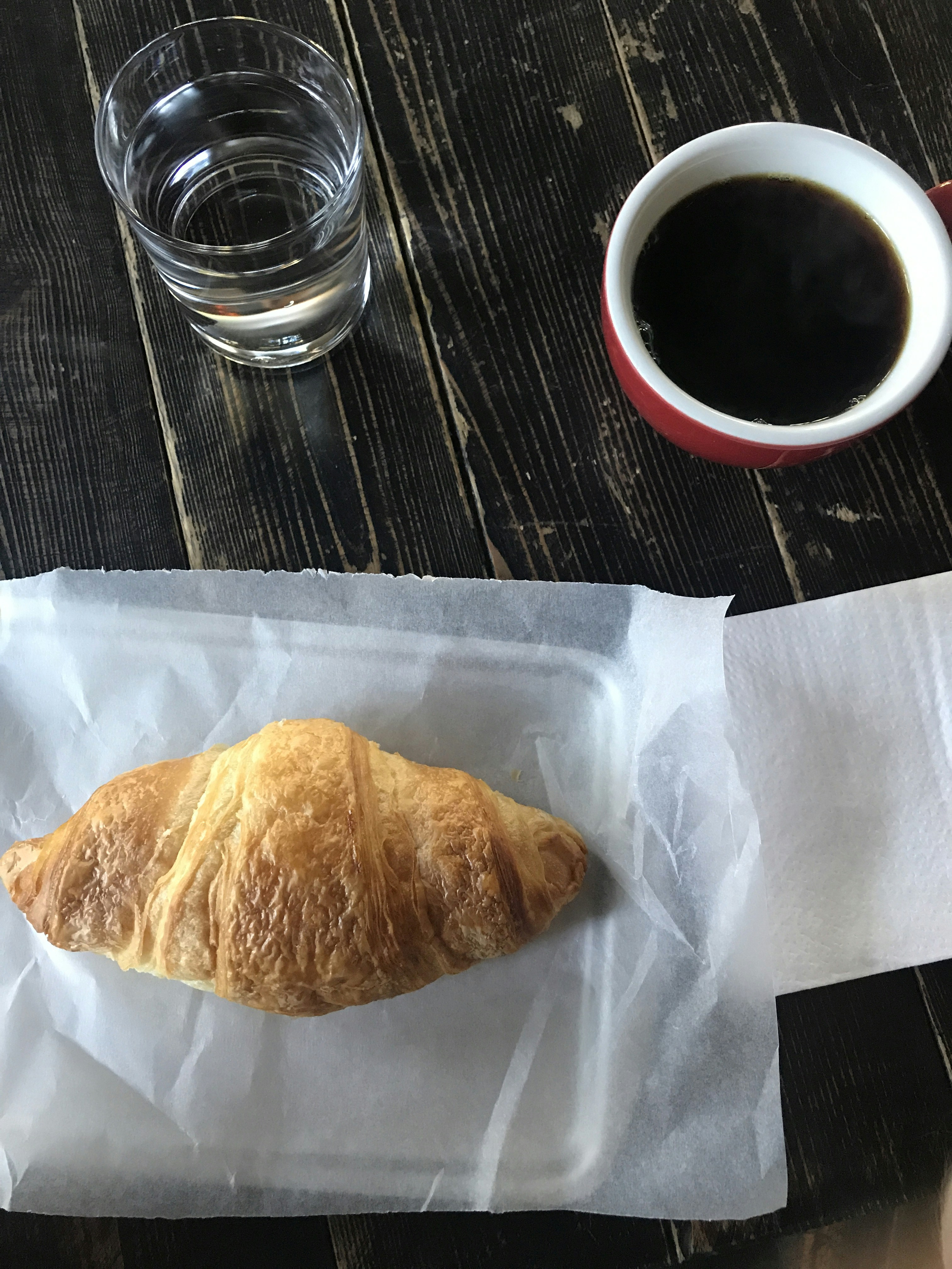 pane su carta bianca accanto al bicchiere trasparente
