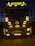 A large truck with multiple bright yellow lights around its front. The word 'ROTASIZ' is illuminated on top of the truck. Some details and symbols, including a central emblem, are visible on the grill and bumper. The vehicle is stationary against a dark background, giving a sense of night or low-light conditions.