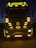 A large truck with multiple bright yellow lights around its front. The word 'ROTASIZ' is illuminated on top of the truck. Some details and symbols, including a central emblem, are visible on the grill and bumper. The vehicle is stationary against a dark background, giving a sense of night or low-light conditions.