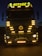 A large truck with multiple bright yellow lights around its front. The word 'ROTASIZ' is illuminated on top of the truck. Some details and symbols, including a central emblem, are visible on the grill and bumper. The vehicle is stationary against a dark background, giving a sense of night or low-light conditions.