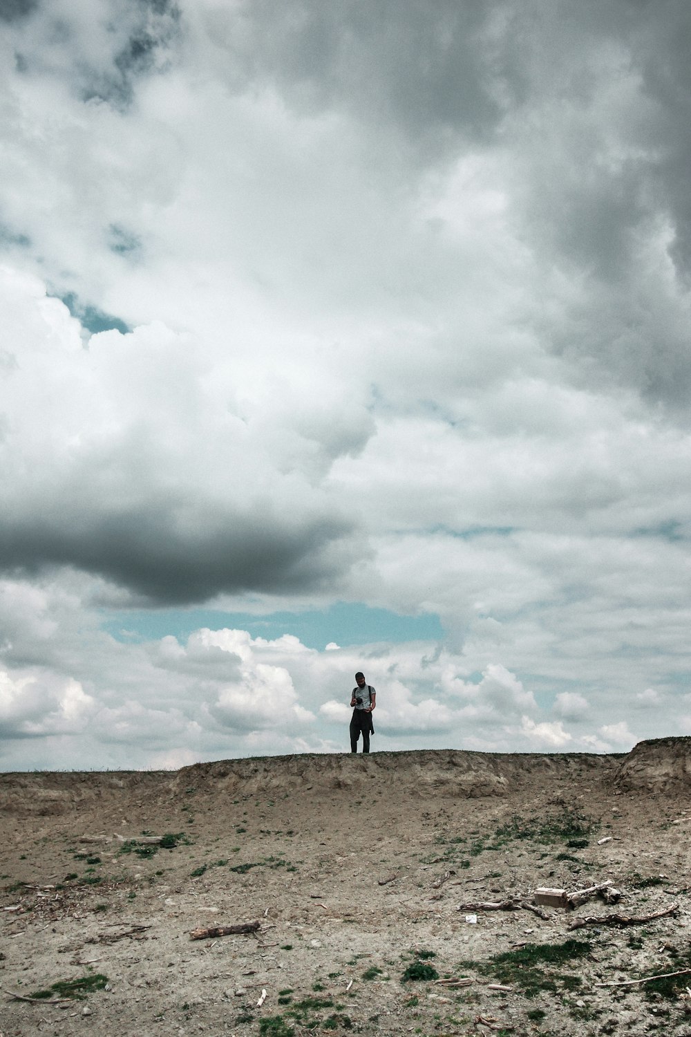 pessoa em pé no campo marrom sob nuvens brancas durante o dia