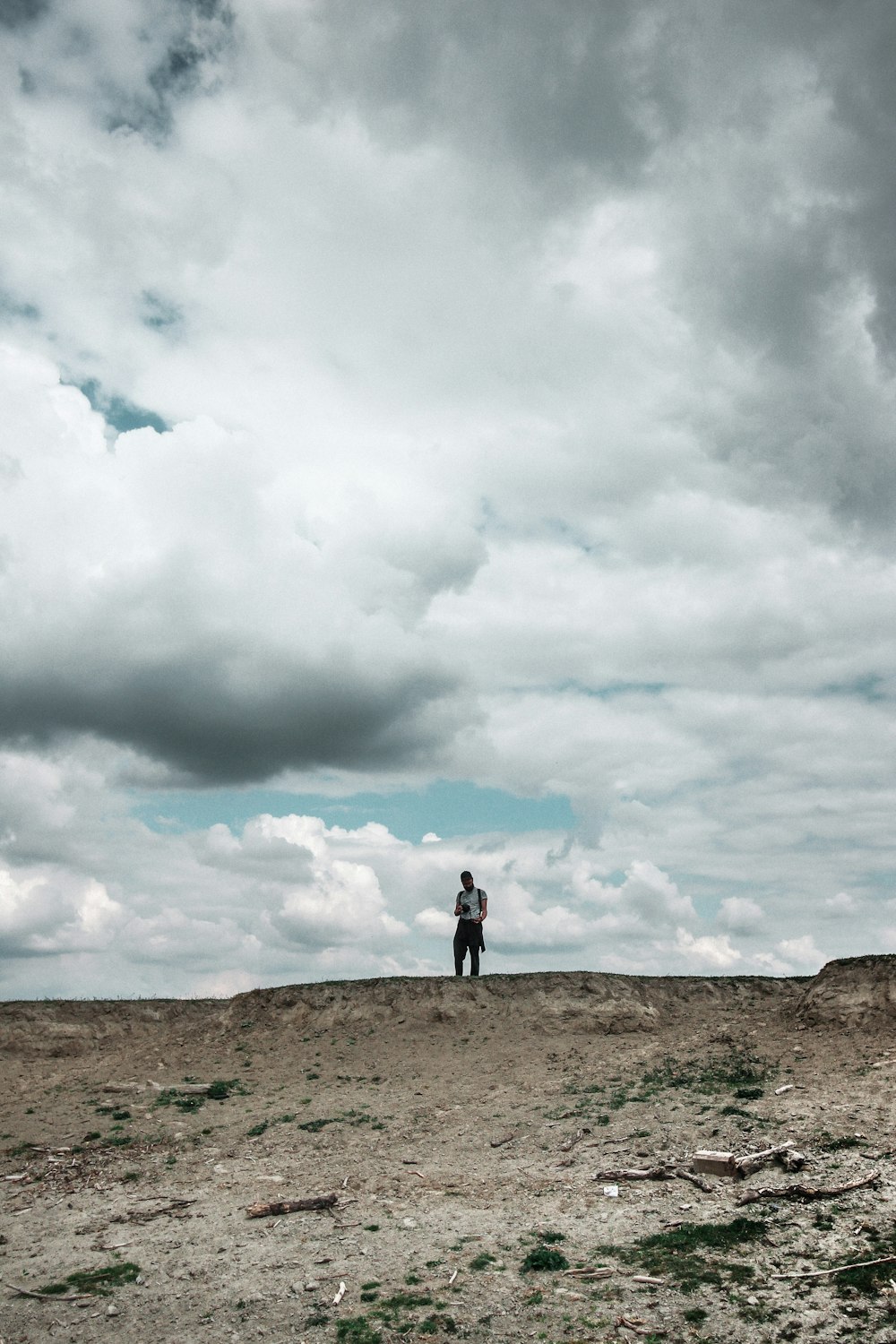 Person, die tagsüber auf braunem Feld unter weißen Wolken steht