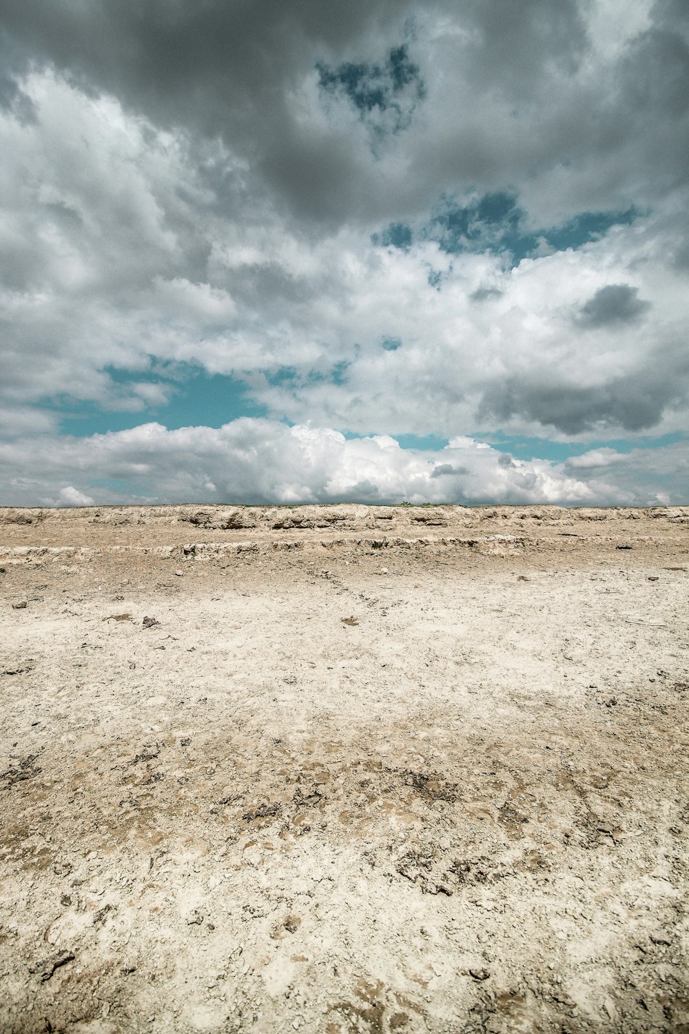 brown field under white clouds and blue sky during daytime