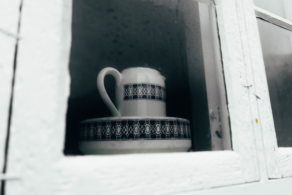white and black ceramic mug on white wooden table