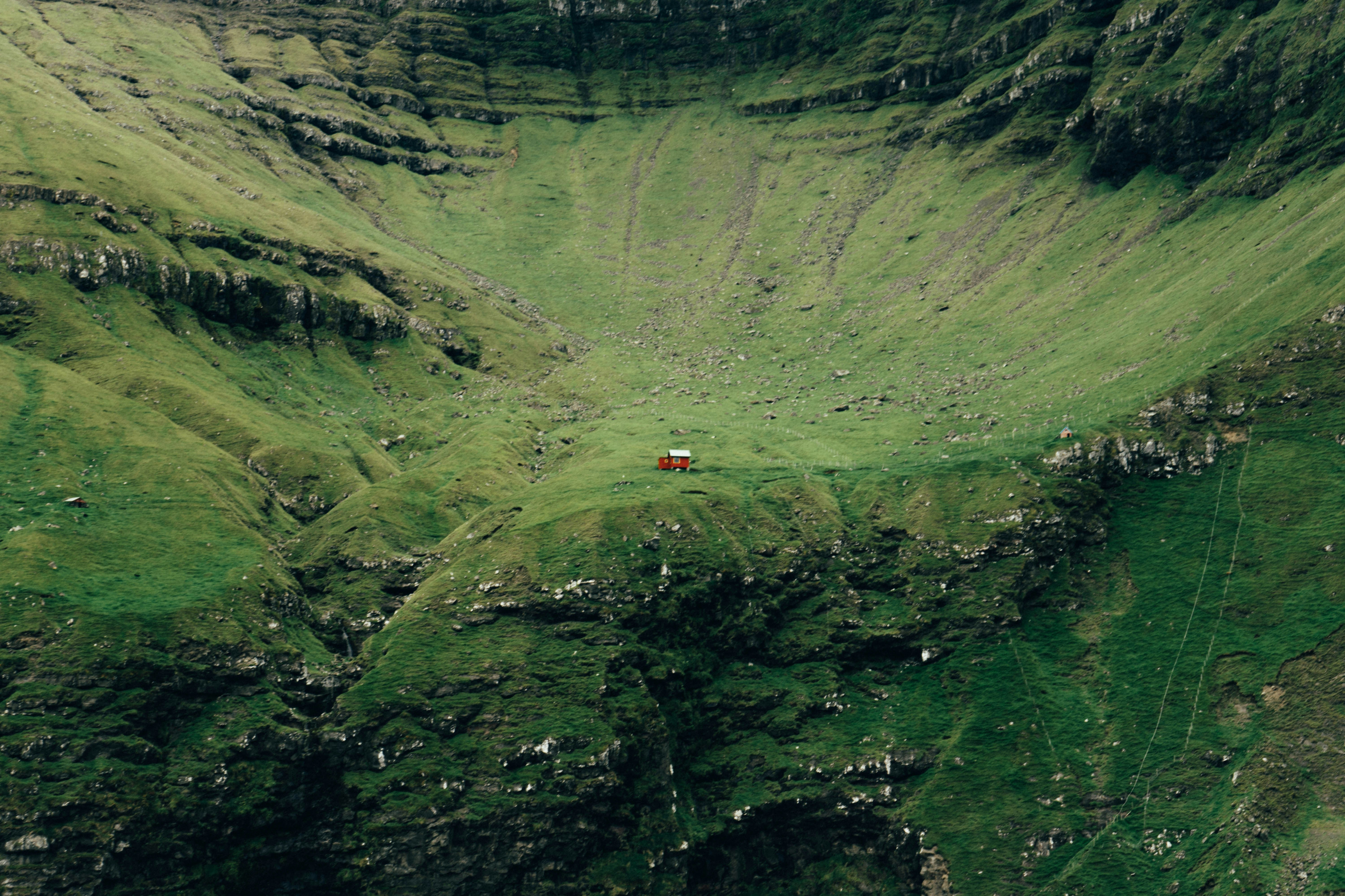red car on road in between green mountains during daytime, 
