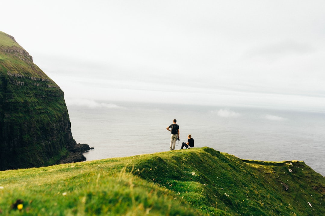 person standing on green grass field near body of water during daytime