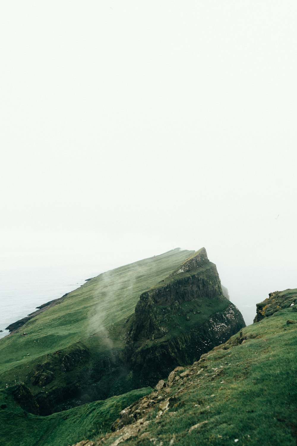 green and gray mountain beside body of water during daytime