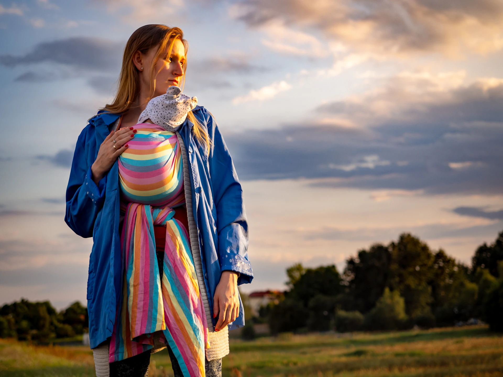 woman in blue pink and yellow dress standing on green grass field during daytime