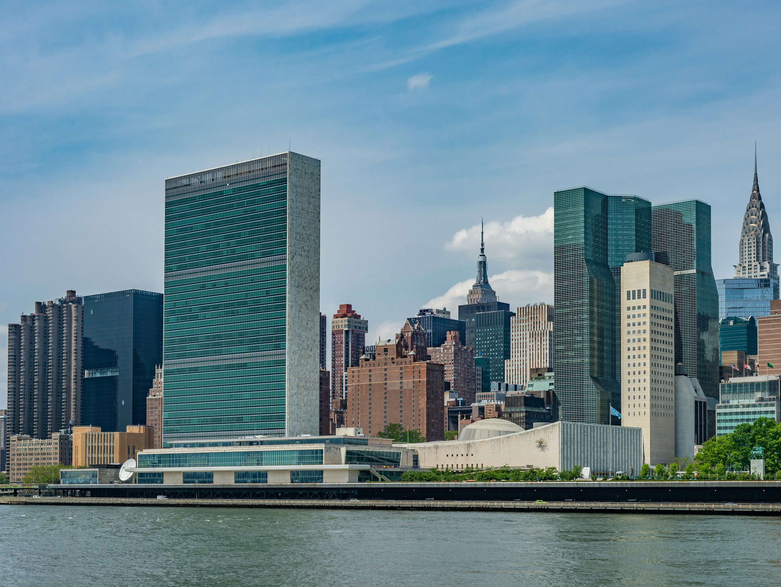 A rare view of the Manhattan skyline from Roosevelt Island, with the United Nations building in the foreground and the Empire State and Chrysler buildings visible. 