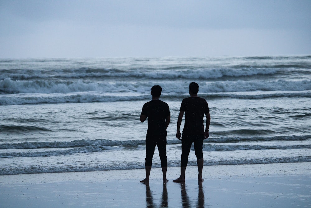 2 men standing on seashore during daytime