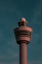 A sleek control tower bathed in soft pink and blue light at dusk.