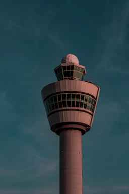 A sleek control tower bathed in soft pink and blue light at dusk.