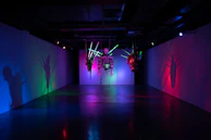 A creative exhibition setup featuring sculptural elements and ambient lighting in a dark room.