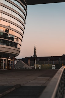 Modern urban church building with glass walls reflecting the city skyline at dusk.