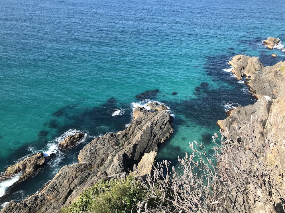 formação rochosa marrom ao lado do mar azul durante o dia