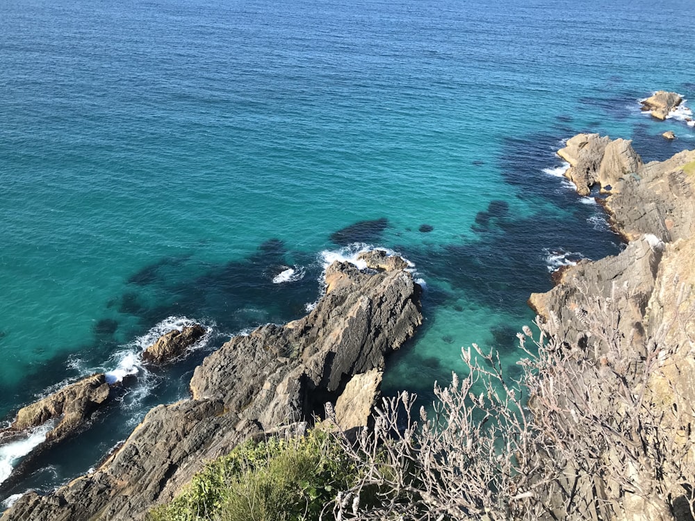 Formación rocosa marrón junto al mar azul durante el día