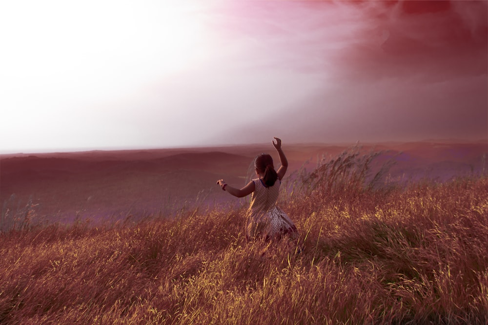 woman in white dress sitting on brown grass field during daytime