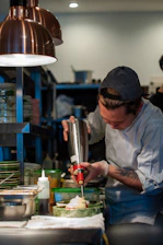 Technician carefully applying pest control treatment in a residential kitchen.
