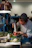 Close-up of a chef using a digital thermometer in a bustling restaurant kitchen.