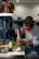 Close-up of a chef using a digital thermometer in a bustling restaurant kitchen.