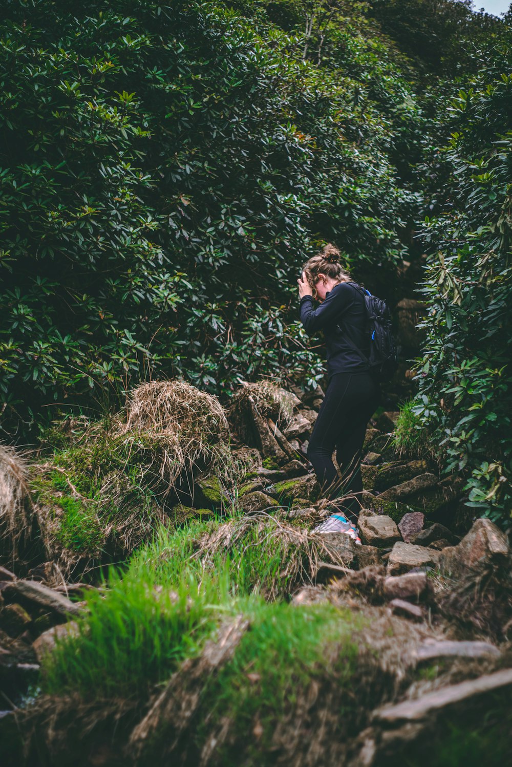 woman in black jacket and black pants sitting on rock