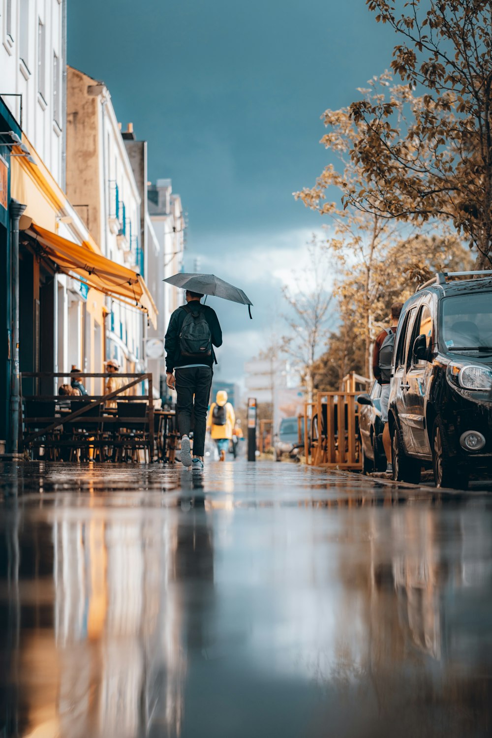 person in black jacket holding umbrella standing on sidewalk during daytime