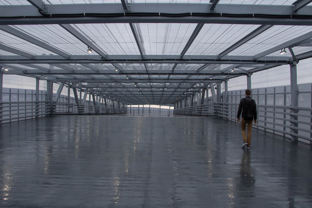 man in black shirt walking on gray concrete floor