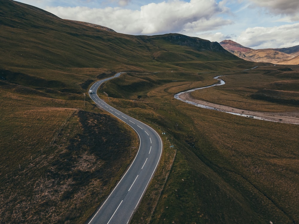 gray concrete road in the middle of green grass field