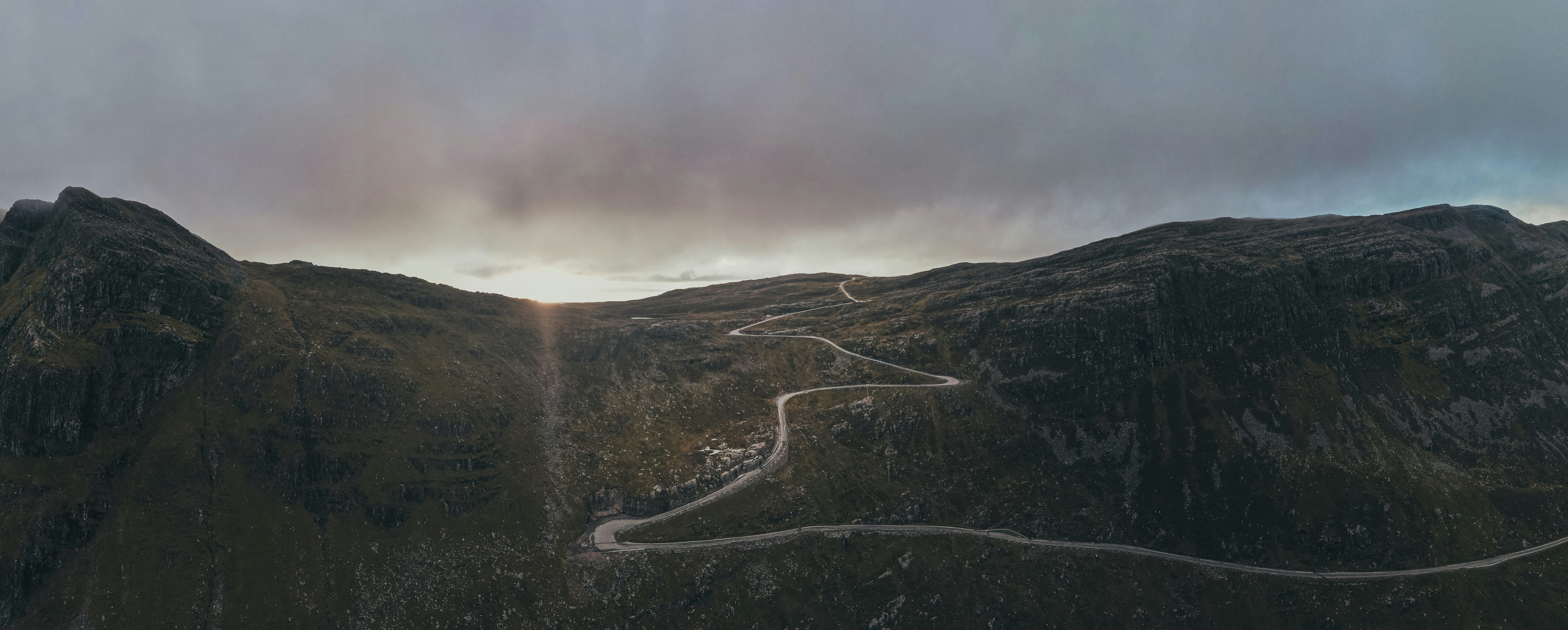 gray road in the middle of green mountains