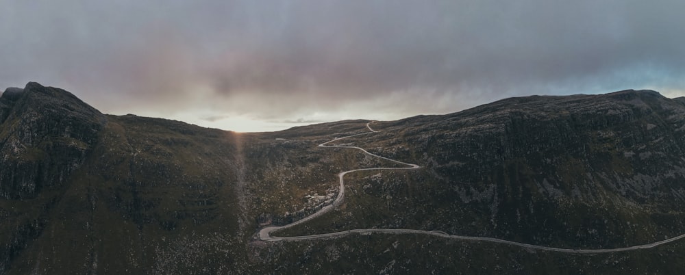 gray road in the middle of green mountains