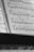 A close-up view of open sheet music showing musical notes and staff lines on pages. The focus is sharp on the notes, highlighting the intricate details of the musical composition. The image is captured in black and white, giving it a classic and timeless feel.